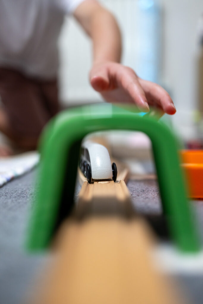 Child and adult hands holding a wooden toy figure together in the playroom